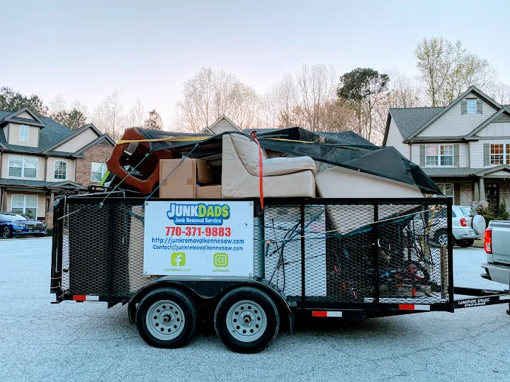 Junk Dads trailer loaded with couches and boxes on a neighborhood street